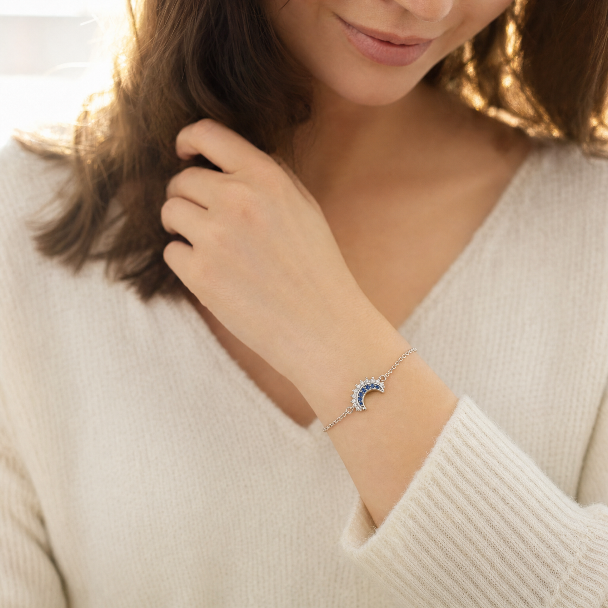 Wearing the moon bracelet, wrist raised in the light